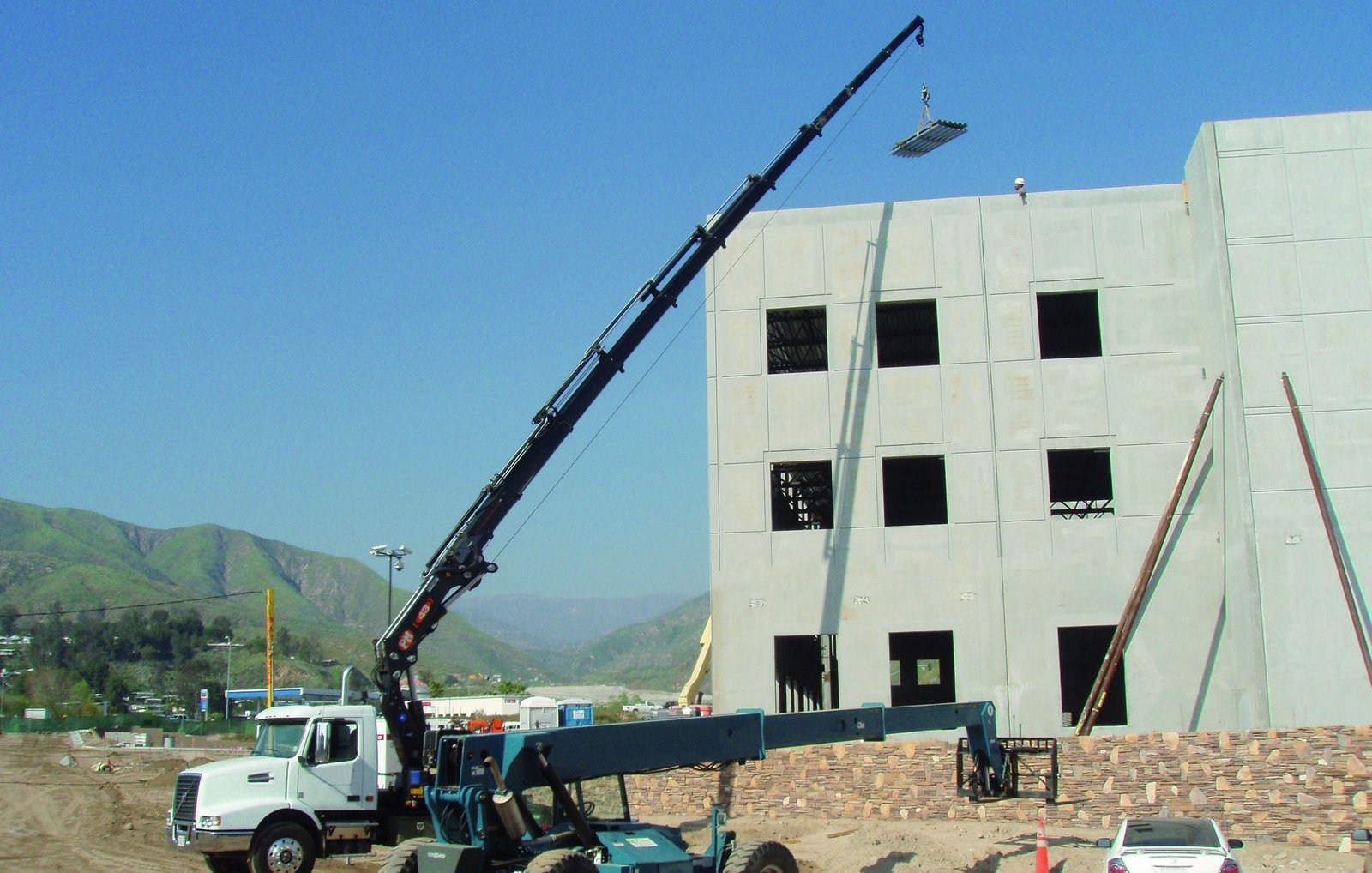 PM knuckle boom crane placing a panel on a precast building